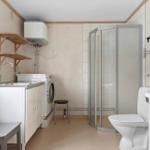 Badezimmer mit Dusche, Toilette, Waschmaschine und Waschbecken.