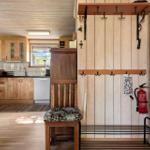 Eingangsbereich mit Kleiderhaken und Feuerlöscher. Küche mit Holzmöbeln und Fenster.