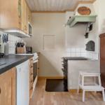 Küche mit Holzmöbeln, Steinplatten und altem Ofen