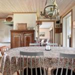 Esszimmer mit runden Tisch, Stühlen und Holzdecke. Küche und Wohnzimmer sind sichtbar.