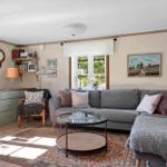 Wohnzimmer mit Sofa, Couchtisch und Wandbildern. Fenster mit Blick auf Grün.