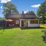 Rotes Haus mit weißem Anbau, Garten und Terrasse mit Sonnenschirm.