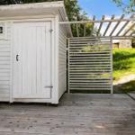 Weiße Holzgarage mit Grill und Pergola auf Holzterrasse