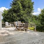 Terrasse mit Tisch, Stühlen und Sicht auf grüne Bäume.
