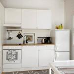 Küche mit weißen Schränken, Kühlschrank und Kochfeld.