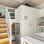 Küche mit Arbeitsplatte, Stufen zum Schlafbereich, weiße Wände und Holzdecke.