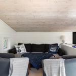 Wohnzimmer mit Sofa, zwei Sesseln und Fernseher an der Wand.