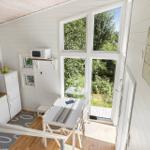 Küche mit Tisch, Fenster und Kühlschrank. Wandbild und Holzboden.