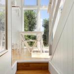 Durchgehendes Fenster mit Tisch und Stühlen. Blick auf grüne Bäume und Himmel.