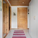 Hallway with wooden ceiling, white walls, wooden doors, and a red rug.