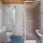 Bathroom with shower, sink, and toilet. Window with curtain and washing machine.