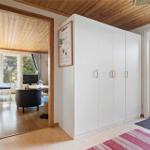 Bright entrance hall with white cabinets and wooden floor. Corridor to living room and balcony.