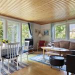 Living and dining area with wooden ceiling, windows, and furniture.