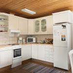 Kitchen with white cabinets, refrigerator, and window with curtains.