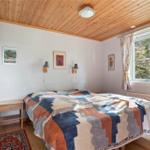 Bedroom with wooden ceiling, bed, and window with curtains.