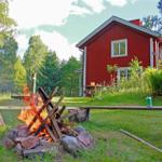 Red wooden house with grill area and campfire in the garden.
