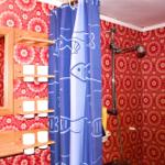 Bathroom with floral wallpaper, blue shower curtain, and wooden shelves.