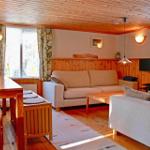 Living room with sofa, dining table, and wooden ceiling. Windows with curtains.