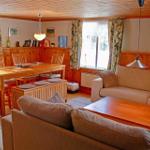 Living and dining area with wooden furniture, sofa, and view of the forest.