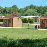 Zwei Holzhütten mit Terrassen stehen auf einer grünen Wiese.