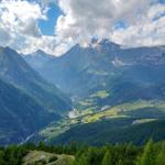 Panoramablick auf eine tief eingeschnittene Berglandschaft mit grünen Hängen und einem Tal.