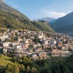 Panoramablick auf ein Bergdorf mit Häusern und umliegenden Bergen.