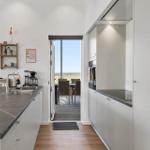 Moderne Küche mit Blick auf Terrasse und Meeresblick.