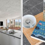 Küche mit Arbeitsplatte und Blick ins Wohnzimmer. Tisch mit Teller, Löffel, Glas und Buch.