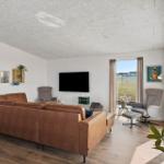 Wohnzimmer mit braunem Sofa, Fernseher und Sicht auf Grünland.