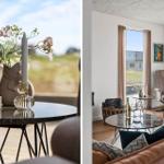 Ein Wohnzimmer mit braunen Sesseln, runden Tischen und großen Fenstern mit Blick auf Felder.