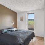 Schlafzimmer mit Bett, Wandlampen und Fensterblick auf Feld.