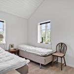 Zwei Betten, zwei Fenster, Stuhl und Holzboden im Schlafzimmer.