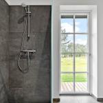 Duschkabine mit dunklen Fliesen und Fenster zum Garten.