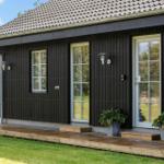 Schwarzes Holzhaus mit Holzterrasse und weißen Fenstern