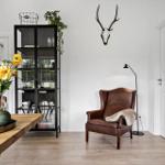 Ein Raum mit braunem Ledersessel, Holzboden und schwarzem Regal.