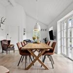 Esszimmer mit Holztisch, braunen Stühlen und großen Fenstern.