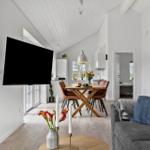 Wohn- und Essbereich mit Fernseher, Tisch und Sofa. Küche im Hintergrund.