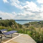 Terrasse mit Liegestühlen und Blick auf See und Hügel.