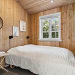 Schlafzimmer mit Holzwand, Bett und Fenster.