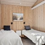 Zwei Einzelbetten mit weißen Bettwäsche und dunklen Kissen an Holzwand.