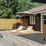 Terrasse mit Liegestühlen, Sonnenschirm und Whirlpool. Holzwand und Holzdecke.