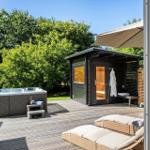 Außenbereich mit Whirlpool, Sauna und Liegen auf Holzterrasse.
