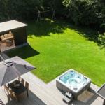 Terrasse mit Whirlpool, Sitzgruppe und Spielplatz im Garten