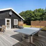 Terrasse mit Tischtennisplatte, Grill und Sitzgruppe vor einem Holzhaus.