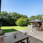 Terrasse mit Grill, Sitzgelegenheiten und Garten. Hintergrund: grüner Rasen und Bäume.