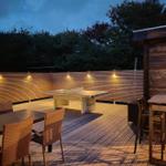 Terrasse mit Tischtennisplatte, Sitzgelegenheiten und Beleuchtung.