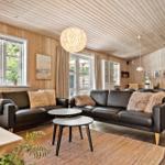 Wohnzimmer mit Holzwänden, zwei schwarzen Sofas und einem runden Tisch.