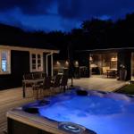 Hochwertiger Außenbereich mit Whirlpool, Terrasse und Grillplatz bei Nacht.