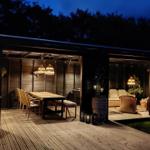 Terrasse mit Essbereich und Loungebereich unter warmen Lichtern.