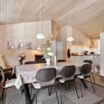 Esszimmer mit Holzwand und Tisch mit Stühlen. Küche im Hintergrund.